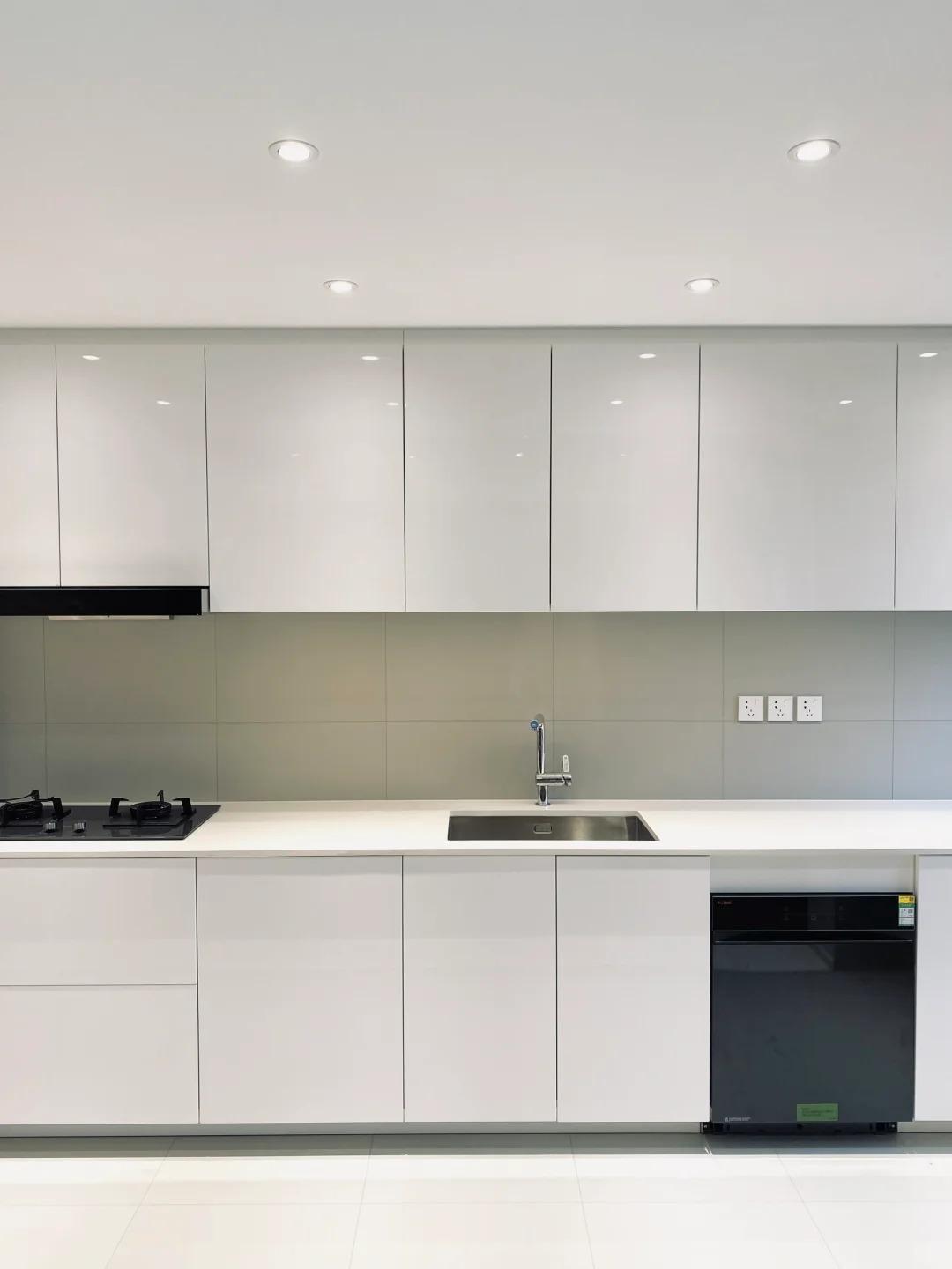 Armadi da cucina bianchi lucidi su misura con piano di lavoro senza giunture, lavello integrato e soluzioni di stoccaggio moderne.