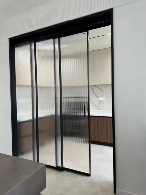 Pintu geser kaca modern dengan rangka logam hitam ramping untuk pembatas ruangan interior kontemporer.